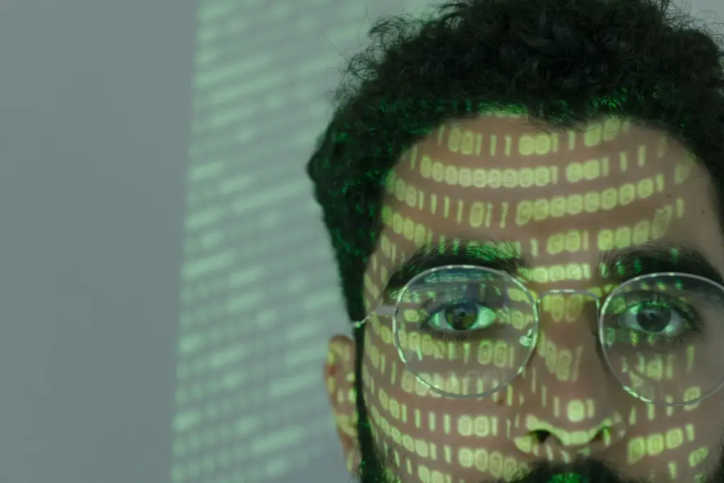 Mann mit projiziertem Binärcode im Gesicht als Symbol für KI-manipulierte Medien