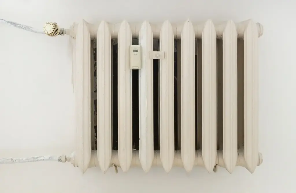 Weißer Heizkörper mit mechanischem Thermostat und sichtbarer Zahlenskala