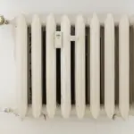 Weißer Heizkörper mit mechanischem Thermostat und sichtbarer Zahlenskala