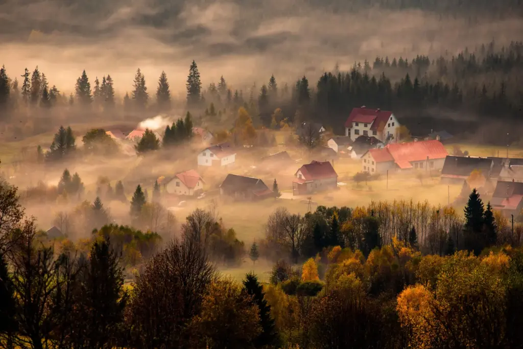 Herbstliches Dorf liegt am Morgen unter einer flachen Nebeldecke