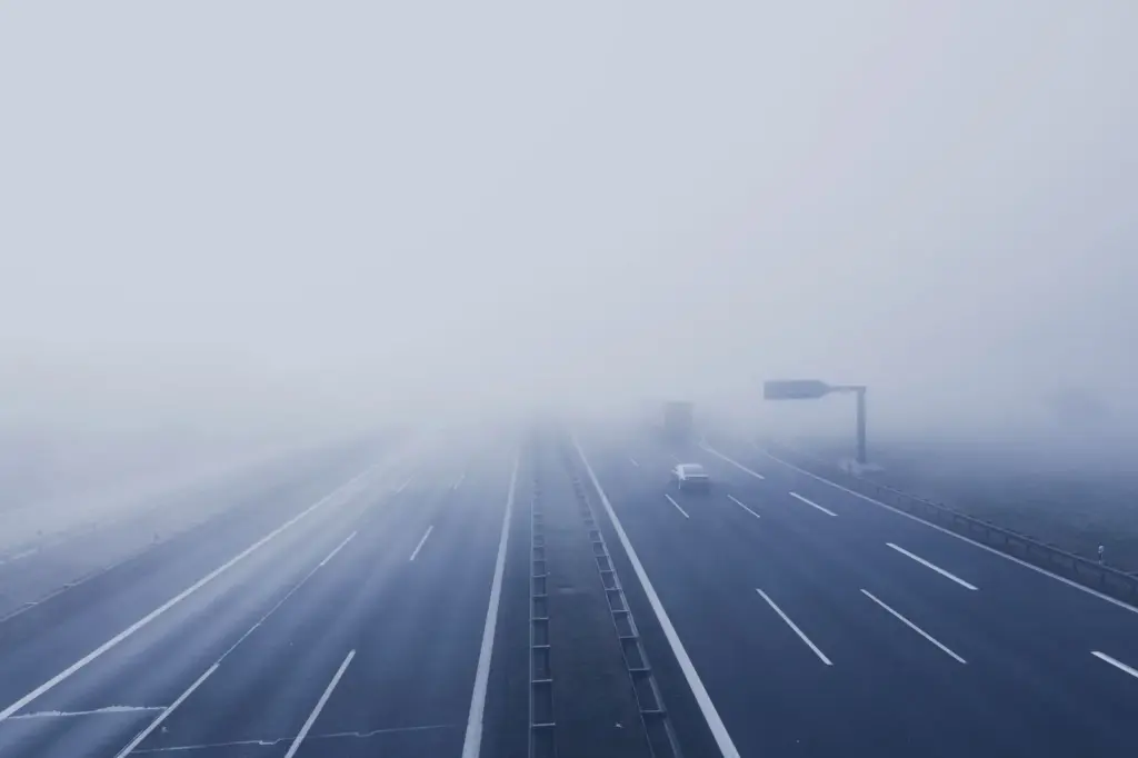 Fahrzeuge fahren auf einer Autobahn in dichtem Nebel mit stark eingeschränkter Sicht