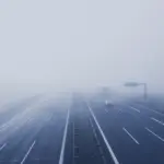 Fahrzeuge fahren auf einer Autobahn in dichtem Nebel mit stark eingeschränkter Sicht