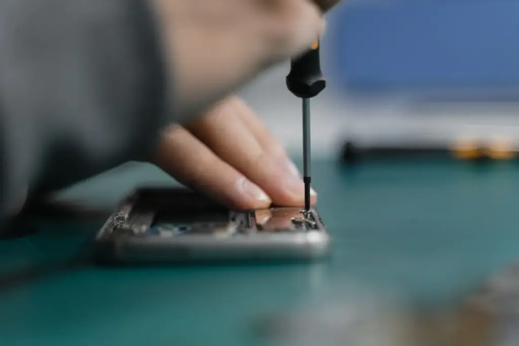 Nahaufnahme einer fachgerechten Smartphone-Reparatur mit einem Schraubendreher
