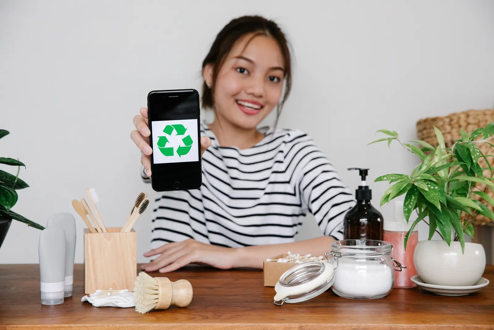 Person zeigt ein grünes Recycling-Symbol auf einem Smartphone