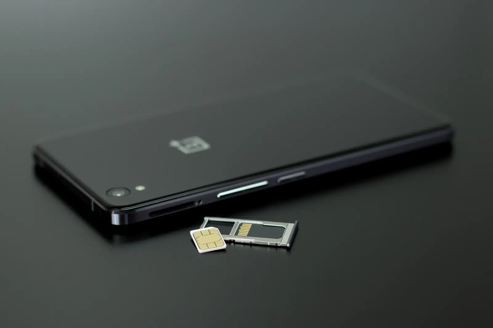 Smartphone neben physischer SIM-Karte, Speicherkarte und Kartenschlitten