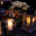 Leuchtende Grablichter und Blumen auf einem Friedhof an Allerheiligen