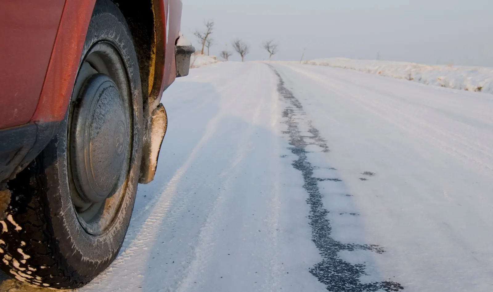 Ein Autoreifen steht auf einer schneebedeckten winterlichen Straße