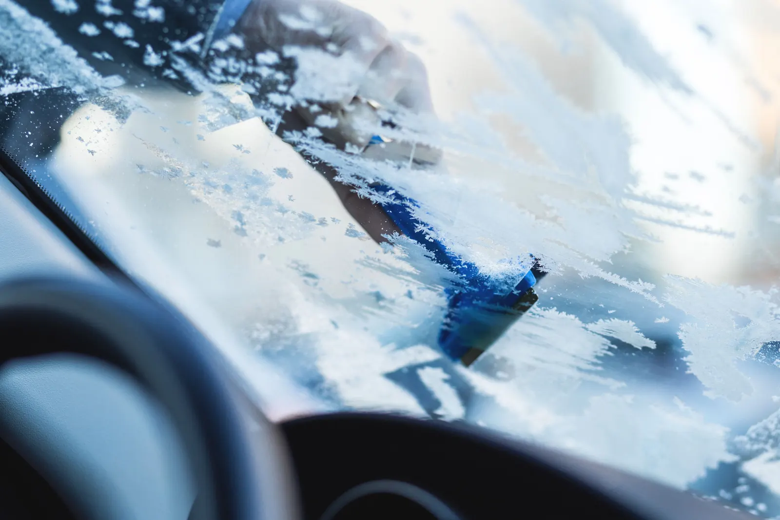 Eiskratzer entfernt Frost von der Windschutzscheibe eines Autos