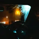 Fahrer sitzt nachts hinter einer von innen beschlagenen Autoscheibe
