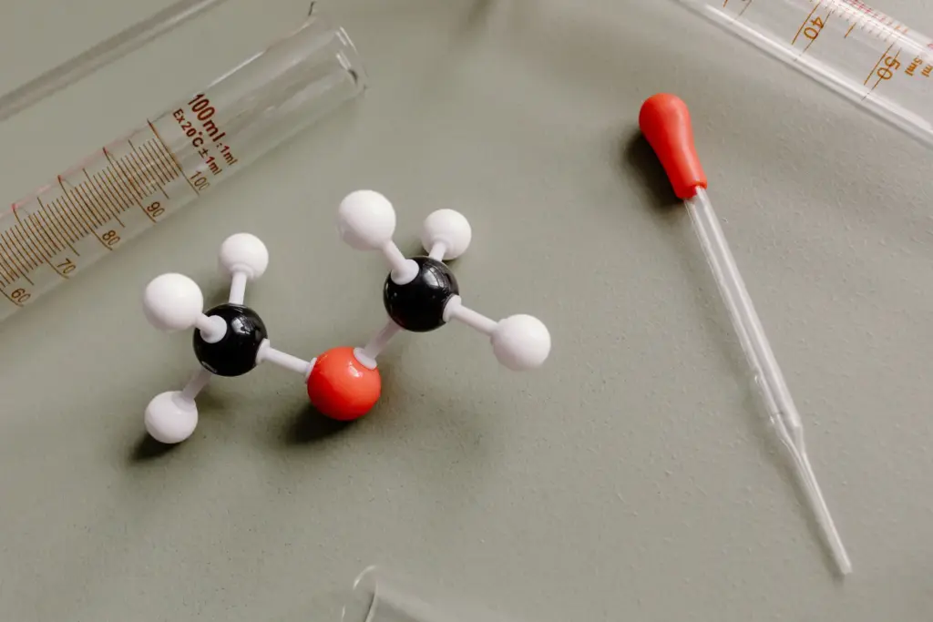 Kugel-Stab-Molekülmodell zwischen Messzylinder und Pipette im Labor