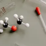 Kugel-Stab-Molekülmodell zwischen Messzylinder und Pipette im Labor
