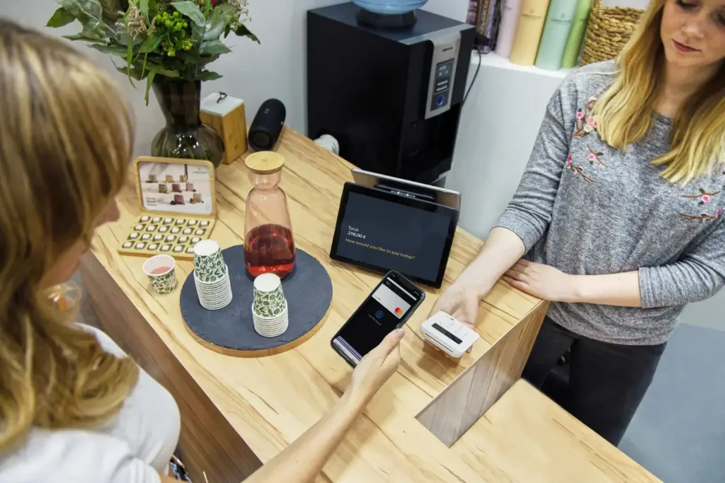 Kundin bezahlt kontaktlos mit einem Smartphone an einem Kassenterminal