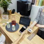 Kundin bezahlt kontaktlos mit einem Smartphone an einem Kassenterminal