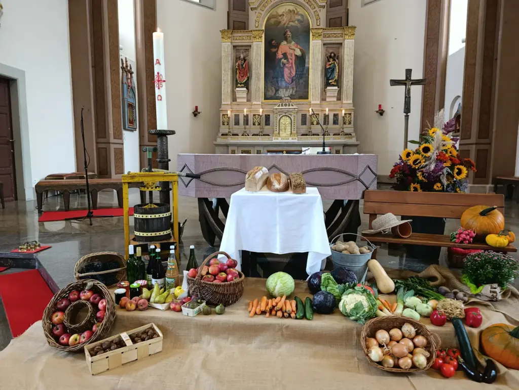 Mit Brot, Obst und Gemüse geschmückter Erntedankaltar in einer Kirche