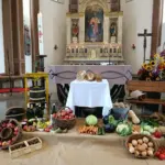 Mit Brot, Obst und Gemüse geschmückter Erntedankaltar in einer Kirche