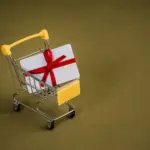 Geschenkgutschein mit roter Schleife in einem kleinen Einkaufswagen