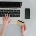 Person gibt am Laptop Daten für eine Online-Zahlung ein