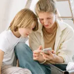 Mutter und Sohn richten gemeinsam ein Smartphone ein
