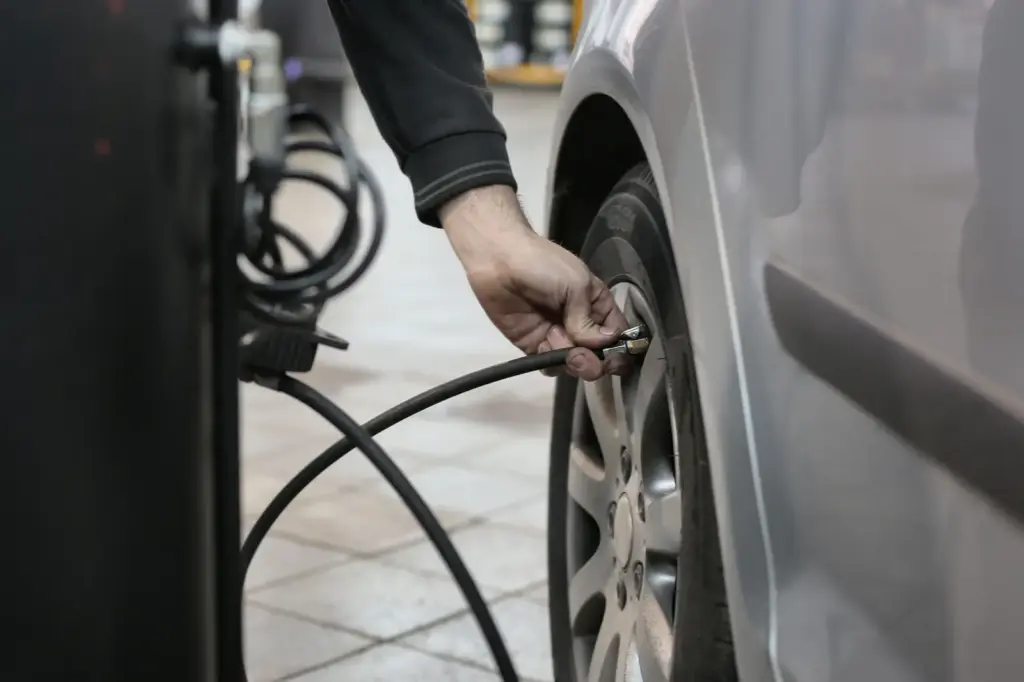 Eine Person setzt den Luftschlauch am Ventil eines Autoreifens an