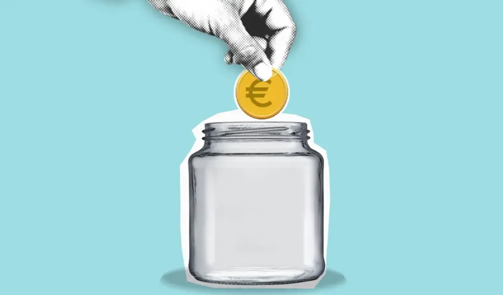 Eine Hand legt eine Euro-Münze in ein Sparglas